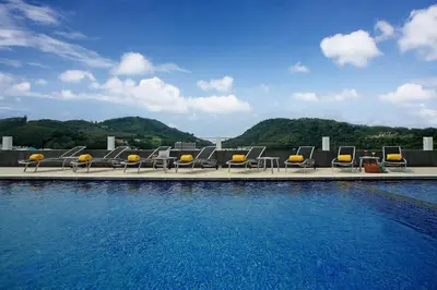 a row of lounge chairs sitting next to a swimming pool at ASHLEE Hub Hotel Patong in Patong Beach