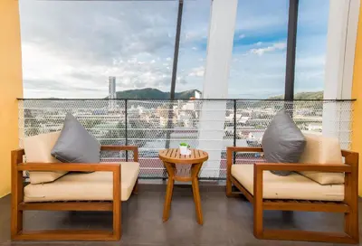 a balcony with two chairs and a table and a window at ASHLEE Hub Hotel Patong in Patong Beach