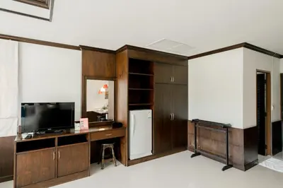 a room with a refrigerator and a desk with a television at The Panwa Guesthouse, Phuket in Panwa Beach