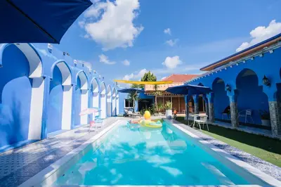 a swimming pool with a blue and white building at The Panwa Guesthouse, Phuket in Panwa Beach