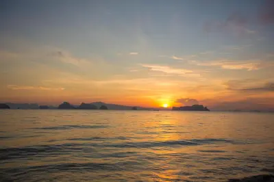 a sunset over the water with mountains in the background at Bungalow VILLA Rumba in Ko Yao Noi