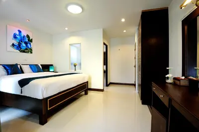 a bedroom with a large bed and a wooden dresser at Ruen Buathong Boutique Hotel Patong Beach in Patong Beach