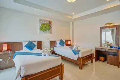 a hotel room with two beds and a window at Ruen Buathong Boutique Hotel Patong Beach in Patong Beach