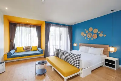 a bedroom with a large bed and a yellow bench at Signature Phuket Resort in Chalong