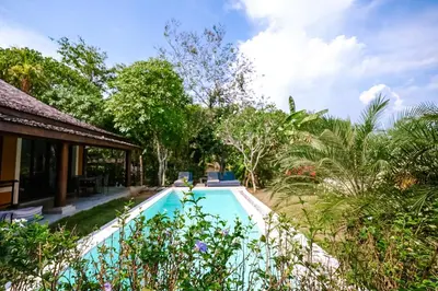 a swimming pool in front of a house with trees at Bungalow VILLA Cha Cha in Ko Yao Noi