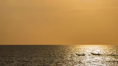 two boats in the ocean at sunset at Jivana Beach Villas in Natai Beach