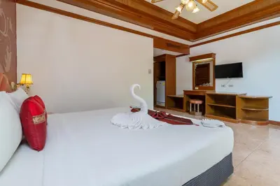 a bedroom with a white bed and a desk at Memory Karon Resort in Karon Beach