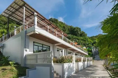 a white house with a balcony with plants at Memory Karon Resort in Karon Beach