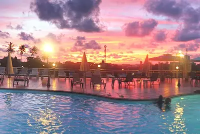 a swimming pool with a sunset in the background at Memory Karon Resort in Karon Beach