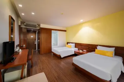 a room with two beds and a desk and a television at Karon Phunaka Resort in Karon Beach