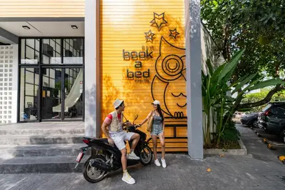 two people sitting on a motorcycle in front of a building at Book a Bed Poshtel - SHA Plus in Phuket Town