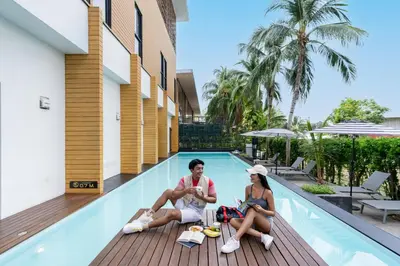 a man and a woman sitting next to a swimming pool at Book a Bed Poshtel - SHA Plus in Phuket Town