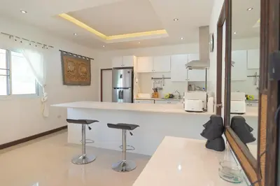 a kitchen with white cabinets and a counter with stools at JUNGLE APARTMENT2 BEDROOMS PRIVATE POOl in Kamala Beach