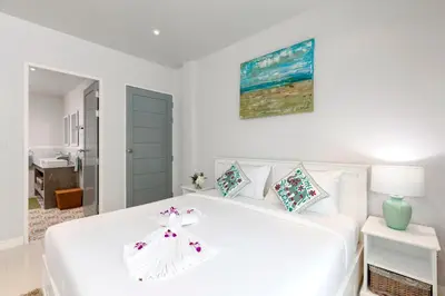 a white bedroom with a white bed and a blue door at Kamala Beach House - 1 min walk to beach in Kamala Beach