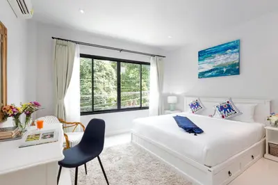 a white bedroom with a bed and a desk and a window at Kamala Beach House - 1 min walk to beach in Kamala Beach