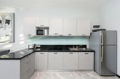a kitchen with white cabinets and a stainless steel refrigerator at VILLA Galam 2BR Private Pool Naiharn beach in Nai Harn Beach