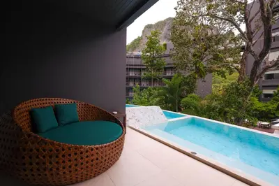 a wicker chair sitting on a balcony next to a swimming pool at Panan Krabi Resort in Ao Nang Beach