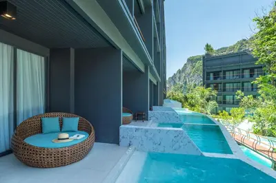 a resort patio with a wicker chair next to a swimming pool at Panan Krabi Resort in Ao Nang Beach