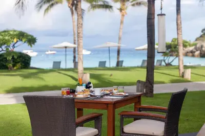a table with chairs and a table with food on it at The Racha in Ko Racha Yai