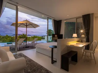a bedroom with a bed and a living room with a view at Villa Abiente in Thalang