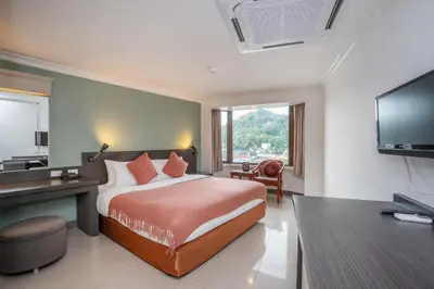 a bedroom with a bed and a desk and a television at I Pavilion Hotel Phuket in Phuket Town