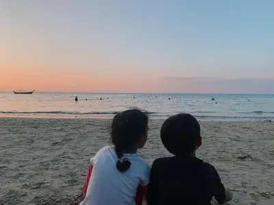 two children sitting on the beach watching the ocean at Ice Kamala Beach Hotel in Kamala Beach