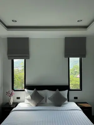 a bedroom with a large bed with two windows at Ice Kamala Beach Hotel in Kamala Beach