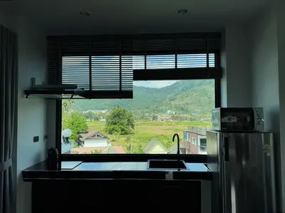 a kitchen with a window with a sink and a refrigerator at Ice Kamala Beach Hotel in Kamala Beach