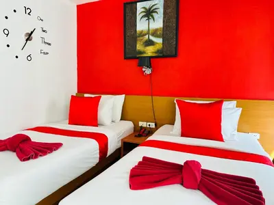 two beds in a room with red walls at PJ Patong Resortel in Patong Beach