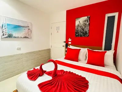two beds in a hotel room with red walls at PJ Patong Resortel in Patong Beach