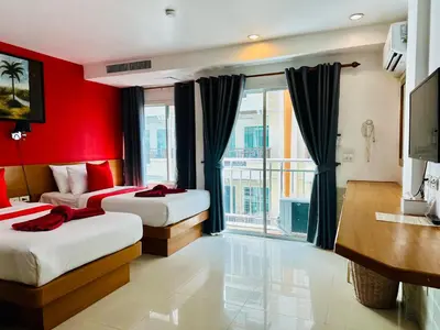 a bedroom with two beds and a red wall at PJ Patong Resortel in Patong Beach