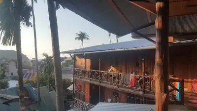 a wooden building with a balcony with a table at Golden Hill Guesthouse in Phi Phi Don