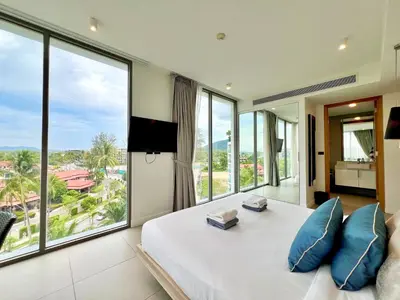 a bedroom with a large bed with a large window at Oceanstone by RESAVA in Bang Tao Beach