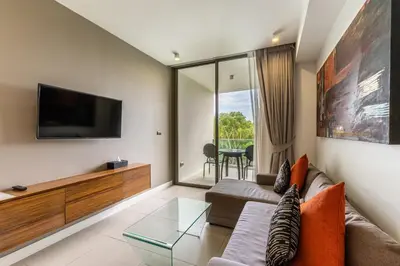 a living room with a couch and a tv at Oceanstone by RESAVA in Bang Tao Beach