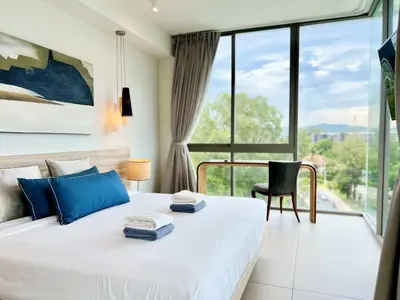 a bedroom with a white bed with blue pillows at Oceanstone by RESAVA in Bang Tao Beach