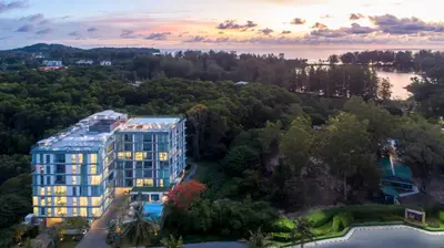 an aerial view of a building with a lake and trees at Oceanstone by RESAVA in Bang Tao Beach