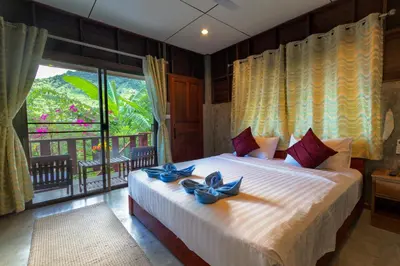 a bedroom with a large bed with blue bows on it at Kanya Cozy Bungalows Kata in Kata Beach
