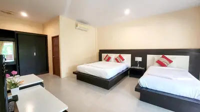 a hotel room with two beds and a table at Sawaddee Aonang Resort in Ao Nang Beach