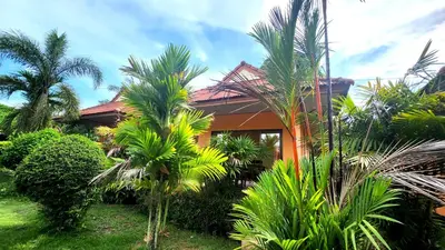a house with palm trees in front of it at Sawaddee Aonang Resort in Ao Nang Beach