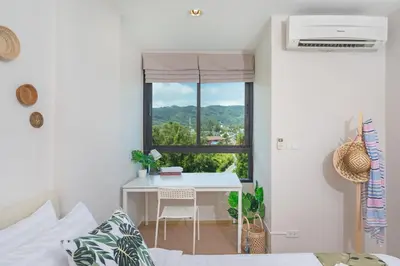 a bedroom with a bed and a desk and a window at ZcapeX2 in Bang Tao Beach