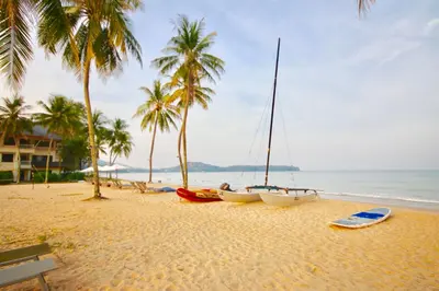 two boats on a beach with palm trees and the ocean at KD Residence in Bang Tao Beach