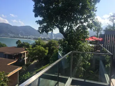 a glass balcony with a view of the water at 5* 3BR SUITE in Amari Phuket - Patong Beach in Patong Beach