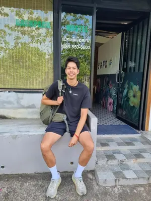 a man sitting on a bench in front of a building at Backpack Hostel Kohyaoyai in Ko Yao Yai