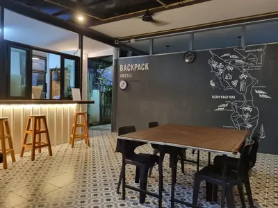 a table and chairs in front of a wall with a map at Backpack Hostel Kohyaoyai in Ko Yao Yai