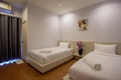 a bedroom with two beds and a vase of flowers at Lin House in Thalang