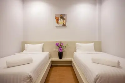 two beds in a room with a vase of flowers at Lin House in Thalang