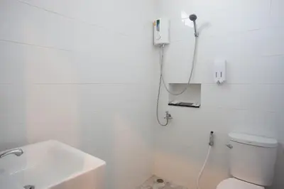 a white bathroom with a toilet and a sink at Lin House in Thalang