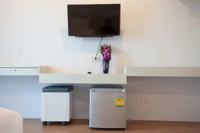 a desk with a tv on a wall with a trash can at Lin House in Thalang