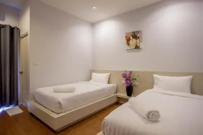 a bedroom with two beds and a vase of flowers at Lin House in Thalang