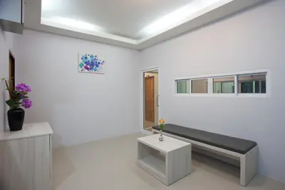 a white room with a bench and a window at Lin House in Thalang